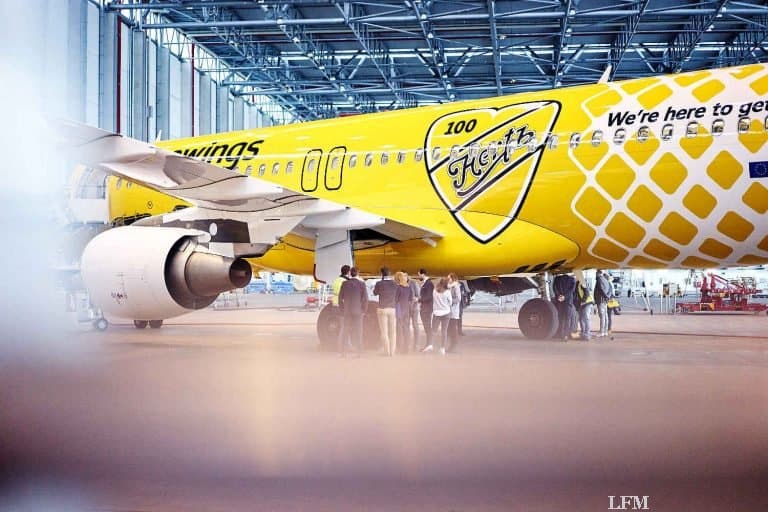 Gelbes Flugzeug von Eurowings fliegt mit Hertz