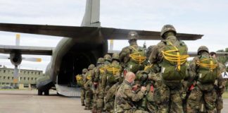 Der Absetzer, ein Sicherheitskontrolleur, überprüft ein letztes Mal, die angelegten Sprunggepäcke bei den Fallschirmjägern, bevor sie in die Transall C-160 einsteigen. (Quelle: Bundeswehr,