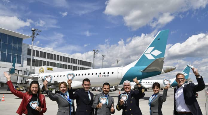 Air Dolomiti feiert rund 30 Millionen München-Reisende in 30 Jahren Die Airlinebetreuer Claudia Metschnabl (links) und Michael Haeffner (rechts) von der Flughafen München GmbH formierten sich vor dem Jubiläumsflug nach Venedig zusammen mit der Crew zum Gruppenbild.