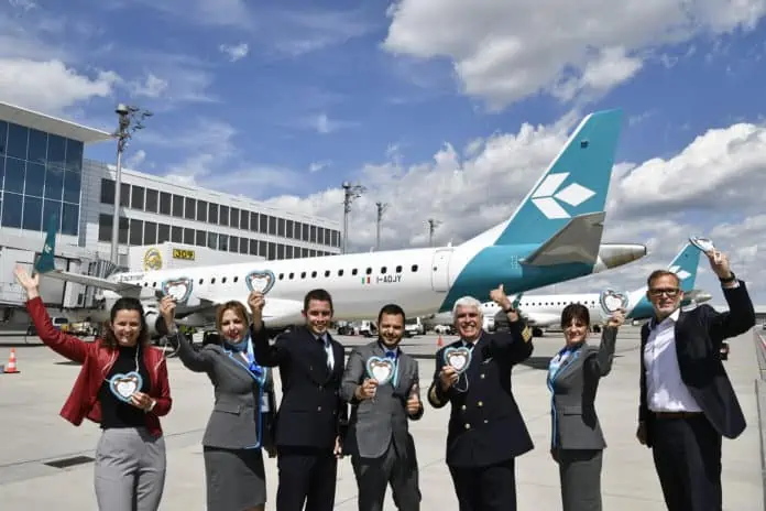 Die Airlinebetreuer Claudia Metschnabl (links) und Michael Haeffner (rechts) von der Flughafen München GmbH formierten sich vor dem Jubiläumsflug nach Venedig zusammen mit der Crew zum Gruppenbild.