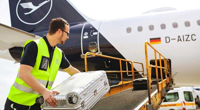 Flughafen München GmbH verkauft Handling an AXS-Gruppe Loader legt Koffer auf das Förderband zur Beladung eines Lufthansa Airbus
