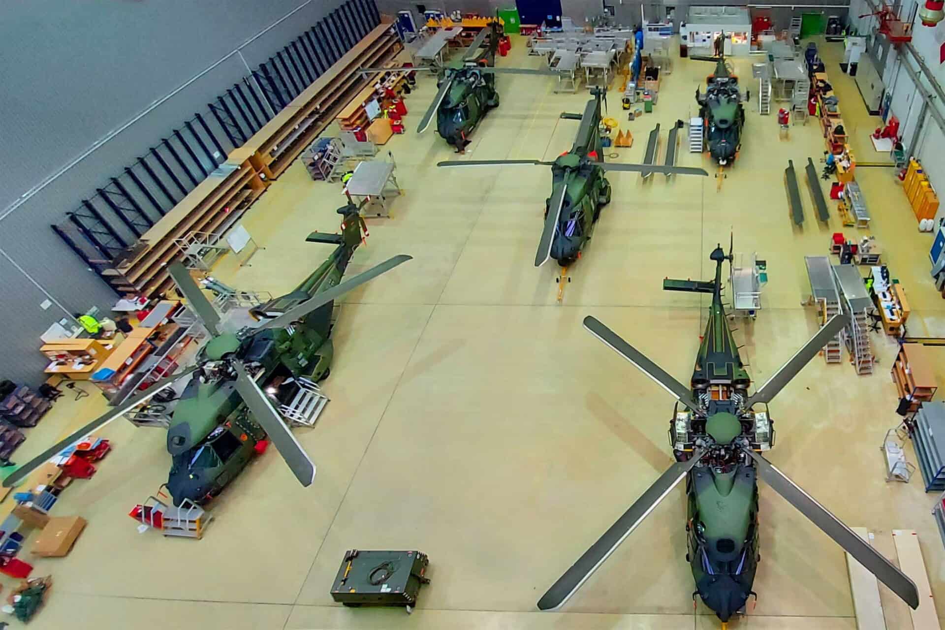 Several military helicopters are parked in a hangar