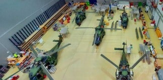 Several military helicopters are parked in a hangar
