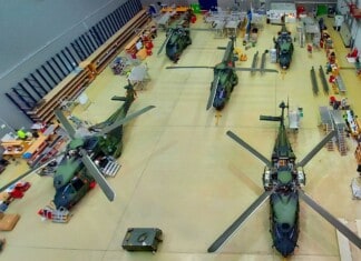 Several military helicopters are parked in a hangar