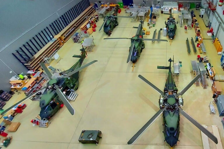 Several military helicopters are parked in a hangar