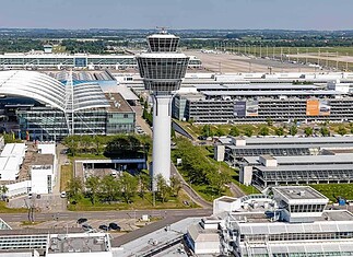 Aerial view of Munich Airport: central zone of the airport featuring the control tower, MAC, terminal access roads, and parking garages.