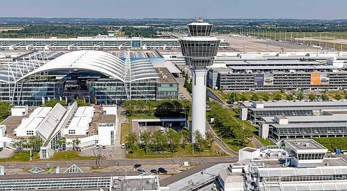 Aerial view of Munich Airport: central zone of the airport featuring the control tower, MAC, terminal access roads, and parking garages.