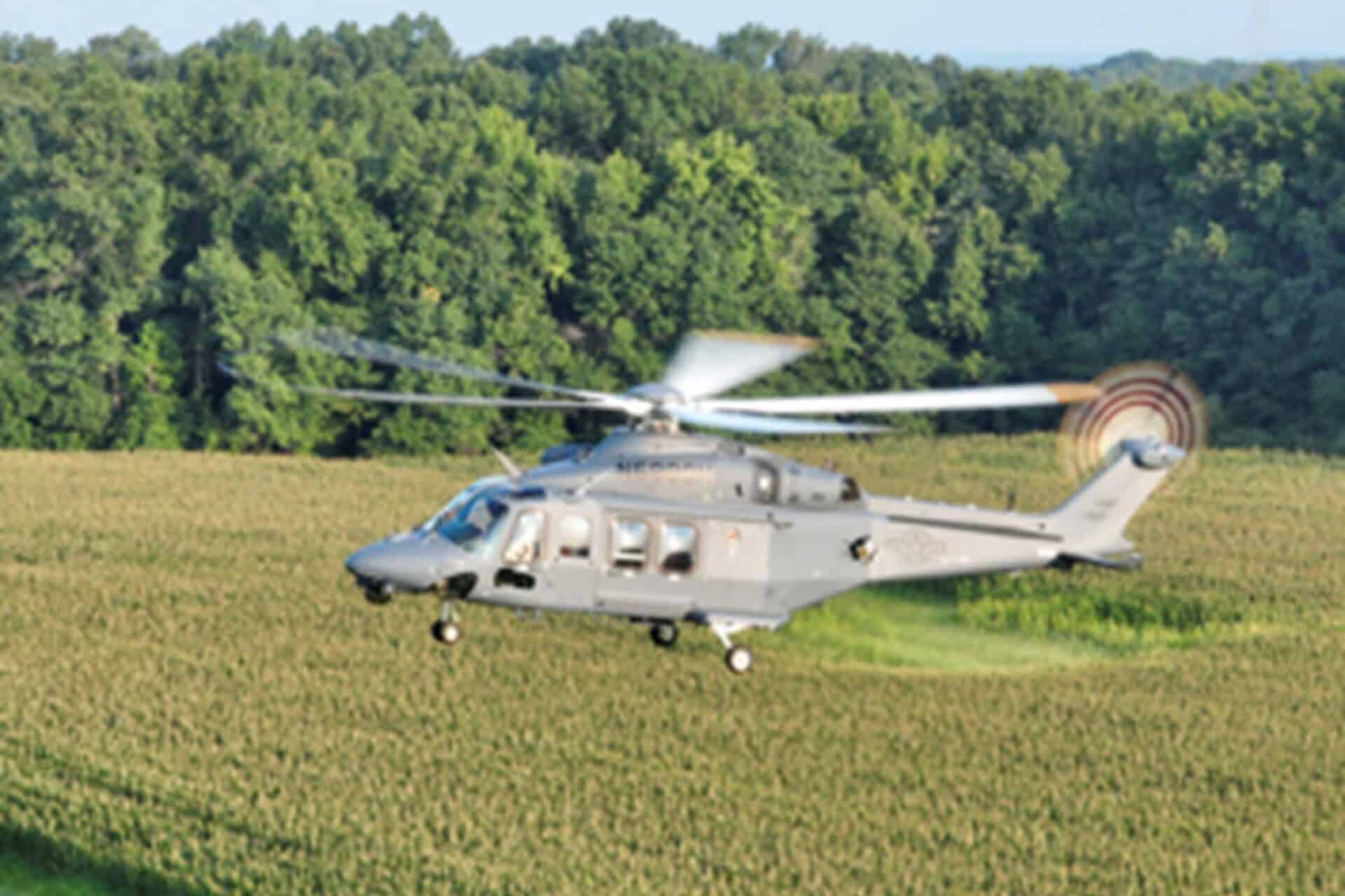 An MH-139A Grey Wolf helicopter flies over fields.