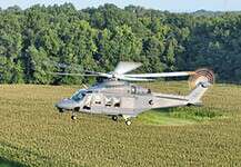 Eine MH-139A Grey Wolf Hubschrauber fliegt über Felder