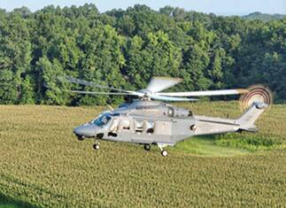 An MH-139A Grey Wolf helicopter flies over fields.