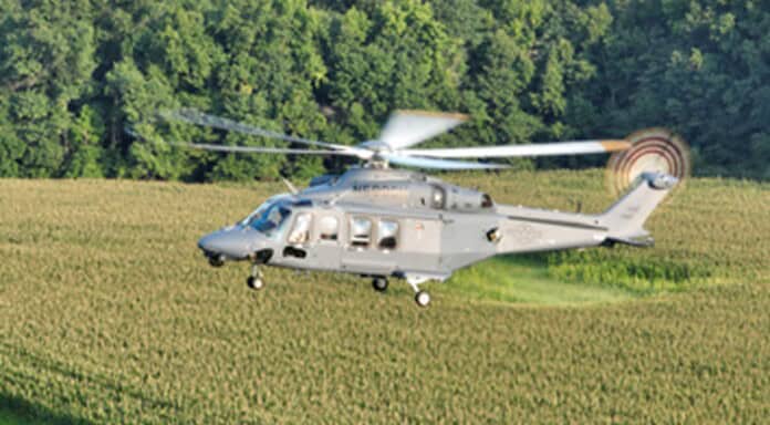 An MH-139A Grey Wolf helicopter flies over fields.