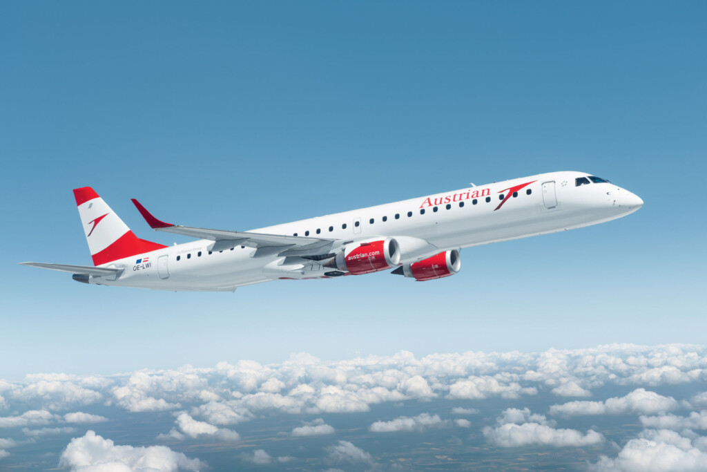 Austrian Airlines E-Jet im Flug über Wolken, klare blaue Himmel.